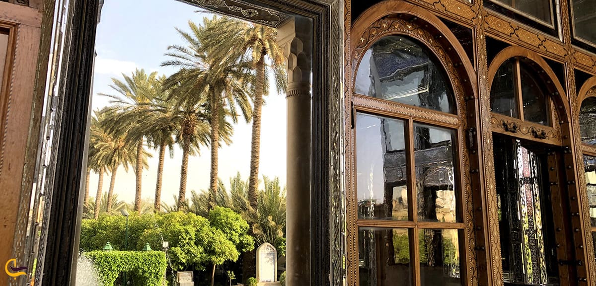 تصویر منعکس شده باغ نارنجستان قوام در آینه آویزان روی در ورودی اندرونی و نمای درها و پنجره های زیبای چوبی باغ نارنجستان قوام شیراز