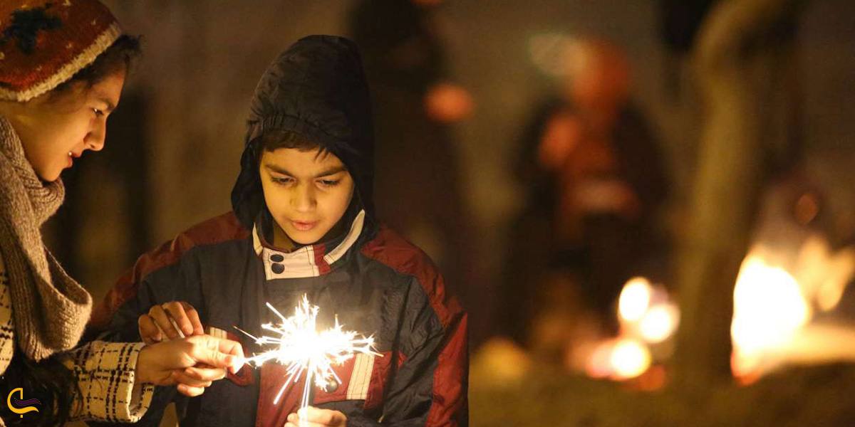 تصویری از پسر بچه در حال روشن کردن ترقه در مراسم چهارشنبه سوری